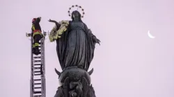 Un pompier monte une longue échelle jusqu'au sommet d'une colonne de près de 40 pieds de haut pour rendre hommage à l'aube à la Sainte Vierge avec une couronne de fleurs, le 8 décembre 2023. | Crédit photo : Daniel Ibanez/CNA / 