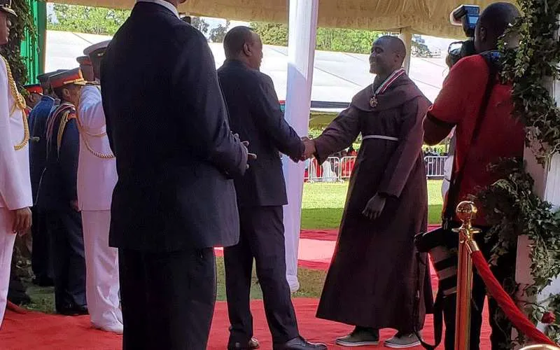 Frère Peter Mokaya Tabichi, Meilleur enseignant du monde recevant le Moran de l'Ordre de la Lance Brûlante à la Maison de l'Etat du Kenya par le Président Uhuru Kenyatta le jour du Jamhuri, 12 décembre 2019 Presse présidentielle