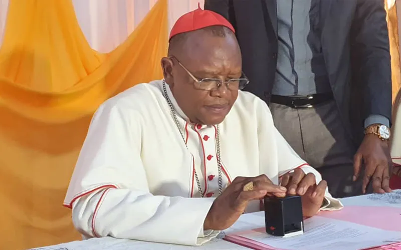 Le Cardinal Fridolin Ambongo signant le décret de création de l'Université Catholique Omnia dans l'archidiocèse de Kinshasa en RD Congo. / 