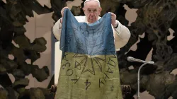 Le pape François brandit un drapeau qui, selon lui, lui a été apporté de "la ville martyre" de Buca, en Ukraine, lors de son audience générale du 6 avril 2022. Vatican Media / 