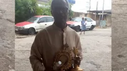 Le Père Benoît Dieme avec l'ostensoir et la lunule contenant le corps du Christ retourné à la paroisse de Rois Mages, à Akebe Ville, dans l'archidiocèse de Libreville au Gabon. / Domaine public