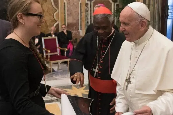 Molly Burhans présente une de ses cartes au pape François et au cardinal Peter Turkson au Vatican durant l'été 2018. Vatican Media