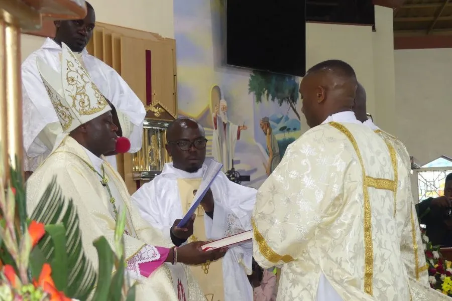 Mgr John Mbinda présente le Livre des Évangiles aux diacres nouvellement ordonnés. Crédit : ACI Afrique / 