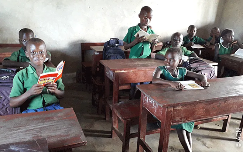 Les enfants de la paroisse Sainte Thérèse de l'Enfant Jésus à Bo, Sierra Leone en train de lire la Bible de l'enfant, "Dieu parle à ses enfants". Aide à l'Église en détresse (AED).